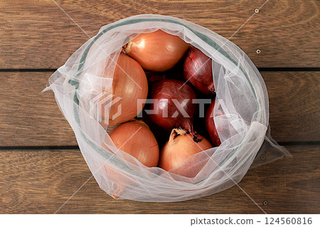 Various varieties of onions in fabric packaging. Healthy natural products in an eco bag to boost immunity, healthy lifestyle concept, zero waste. Banner for the store. No plastic. Selective focus 124560816