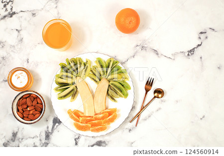 Healthy breakfast with ingredients, fun food for children, ideas for dish decoration, Healthy and natural food concept. Bananas, oranges and nuts in the form of palm trees, selective focus.; 124560914