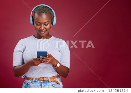 Smartphone, headphone and black woman in studio mock up listening, scroll and typing on music subscription streaming service. African girl using phone audio app on red mockup marketing or advertising Smartphone, headphone and black woman in studio mock up listening, scroll and typing on music subscription streaming service. African girl using phone audio app on red mockup marketing or advertising 124561214