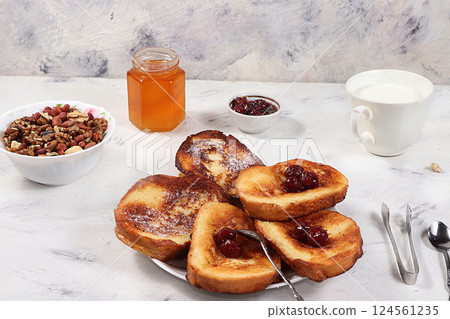 French toasts and granola on a gray table with breadcrumbs. Fried bread with milk and scrambled eggs. Top view, place for text. Minimal concept of a modern bakery. Healthy traditional french 124561235
