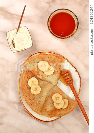 Delicious Russian pancakes with soft cheese, bananas and honey on a marble table. Healthy breakfast with ingredients, carnival concept and traditional national cuisine, selective focus Delicious Russian pancakes with soft cheese, bananas and honey on a marble table. Healthy breakfast with ingredients, carnival concept and traditional national cuisine, selective focus 124561244