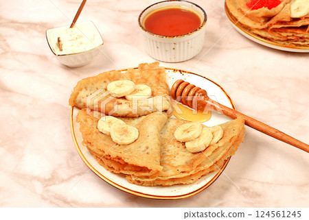 Delicious Russian pancakes with soft cheese, bananas and honey on a marble table. Healthy breakfast with ingredients, carnival concept and traditional national cuisine, selective focus Delicious Russian pancakes with soft cheese, bananas and honey on a marble table. Healthy breakfast with ingredients, carnival concept and traditional national cuisine, selective focus 124561245