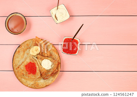 Delicious Russian pancakes with red caviar, soft cheese curd, bananas and honey on a wooden table. Healthy breakfast with ingredients, carnival concept and traditional national cuisine, selective Delicious Russian pancakes with red caviar, soft cheese curd, bananas and honey on a wooden table. Healthy breakfast with ingredients, carnival concept and traditional national cuisine, selective 124561247