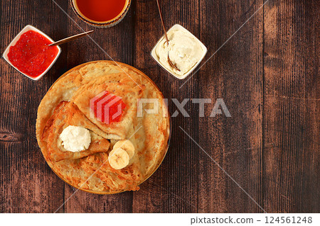 Delicious Russian pancakes with red caviar, soft cheese curd, bananas and honey on a wooden table. Healthy breakfast with ingredients, carnival concept and traditional national cuisine, selective Delicious Russian pancakes with red caviar, soft cheese curd, bananas and honey on a wooden table. Healthy breakfast with ingredients, carnival concept and traditional national cuisine, selective 124561248