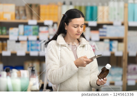 Woman in pharmacy scans QR code on expectorant syrup bottle product 124561336