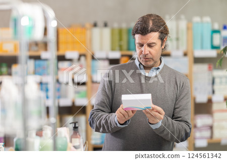 Adult man chooses pills at pharmacy 124561342