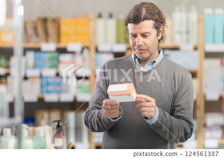Adult man chooses pills at pharmacy 124561387
