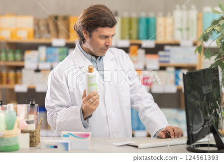 Male pharmacist looking for shampoo on computer 124561393