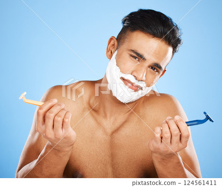Razor, choice and portrait of man with shaving cream making decision to shave beard in studio. Clean, hygiene and guy from India with doubt and shavers to groom face hair isolated by blue background. 124561411