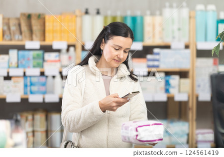 woman scans a package of pads on her phone woman scans a package of pads on her phone 124561419