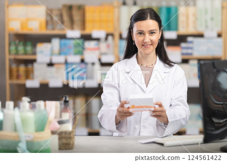 Middle-aged female pharmacist offering preparation in box 124561422