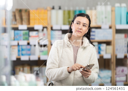 Woman with phone is shopping in pharmacy Woman with phone is shopping in pharmacy 124561431