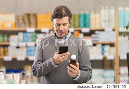 Man in pharmacy scans QR code on expectorant syrup bottle product 124561435