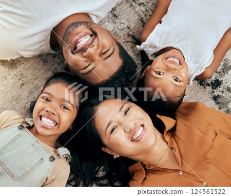 Happy, family and face above on the floor in happiness for bonding time or relaxing together at home. Portrait of mother, father and children faces with big smile for holiday break at the house 124561522