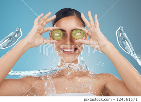 Woman, shower and kiwi for beauty, skincare and eye treatment in a studio with mockup and blue background. Fruit, water and wellness girl model relax, happy and smile with organic, shower and product 124561571