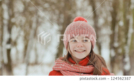 A young schoolgirl joyfully throws a snowball and breaks it with a palm when it falls. Emotions of joy. Winter fun in nature in the forest. A young schoolgirl joyfully throws a snowball and breaks it with a palm when it falls. Emotions of joy. Winter fun in nature in the forest. 124562387