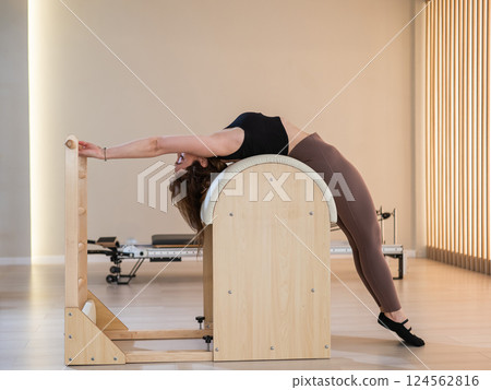 Asian woman exercising on pilates barrel.  124562816