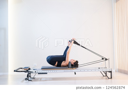Asian woman doing pilates on reformer.  124562874
