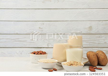 Vegan alternative milk lactose and gluten free, allergy free, almonds, rice, oats, potatoes and glasses of drinks on wooden table, healthy eating concept, diet food, weight loss, 124563351