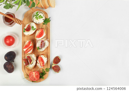 Healthy breakfast with ingredients, toast with figs and soft cream cheese ricotta and honey, canapes or crostini with toasted baguette and herbs on a light sunny table, Italian recipe menu, selective Healthy breakfast with ingredients, toast with figs and soft cream cheese ricotta and honey, canapes or crostini with toasted baguette and herbs on a light sunny table, Italian recipe menu, selective 124564006