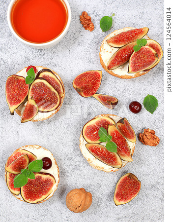 Ricotta,figs and bruschetta with honey on gray marble.Fresh sandwiches and toast with cream cheese,sliced figs,honey and cherries.Healthy breakfast with ingredients,lunch or dessert,diet food 124564014