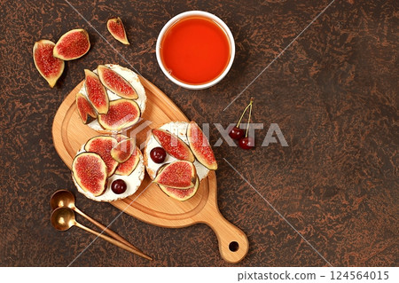 Healthy breakfast with ingredients, toast with figs and soft cream cheese ricotta and honey, canapes or crostini with toasted baguette and herbs on dark concrete table, Italian recipe menu, selective Healthy breakfast with ingredients, toast with figs and soft cream cheese ricotta and honey, canapes or crostini with toasted baguette and herbs on dark concrete table, Italian recipe menu, selective 124564015