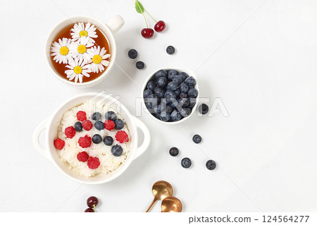 Healthy breakfast with ingredients, milk rice porridge with fresh blueberries, cherries and raspberries, creamy rice pudding or French rice with honey and chamomile tea. Natural nutrition concept, Healthy breakfast with ingredients, milk rice porridge with fresh blueberries, cherries and raspberries, creamy rice pudding or French rice with honey and chamomile tea. Natural nutrition concept, 124564277