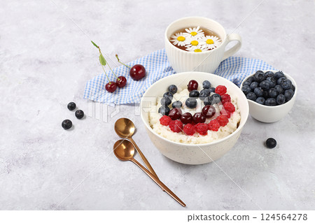 Healthy breakfast with ingredients, milk rice porridge with fresh blueberries, cherries and raspberries, creamy rice pudding or French rice with honey and chamomile tea. Natural nutrition concept, 124564278