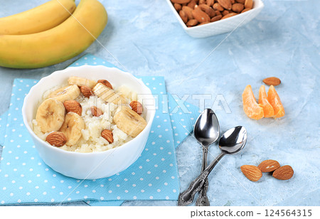 Useful breakfast with ingredients, flat lay, rice pudding with bananas, honey and almonds on a sunny table. Healthy and natural food concept, lifestyle, food for children, selective focus 124564315