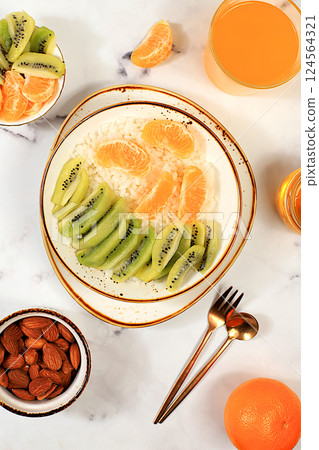 Rice pudding with kiwi, honey, tangerines and almonds. Healthy breakfast with ingredients, flat lay, Healthy and natural food concept, lifestyle, food for children, 124564321
