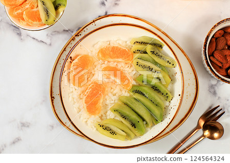 Rice pudding with kiwi, honey, tangerines and almonds. Healthy breakfast with ingredients, flat lay, Healthy and natural food concept, lifestyle, food for children 124564324