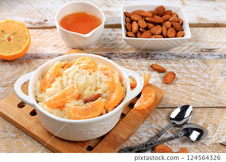 Healthy breakfast with ingredients, flat lay, rice pudding with bananas, honey, tangerines and almonds on a sunny table. Healthy and natural nutrition concept, lifestyle, nutrition for children, 124564326