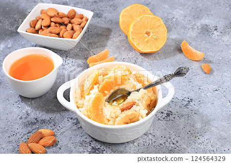 Rice pudding with bananas, honey, tangerines and almonds. Healthy breakfast with ingredients, flat lay, Healthy and natural food concept, lifestyle, food for children, 124564329