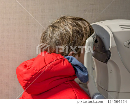 Child looking into a retinal camera medical device for an eye exam Child looking into a retinal camera medical device for an eye exam 124564354