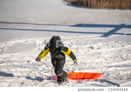 Child pulling a sled up a snow covered hill covered with tracks Child pulling a sled up a snow covered hill covered with tracks 124564356