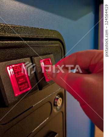 hand Putting a coin into an arcade game slot hand Putting a coin into an arcade game slot 124564419