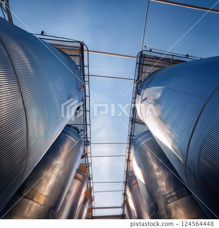 Industrial silos soar towards the sky under a clear blue atmosphere in a modern agricultural complex. Generative AI 124564448