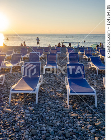 Beach chairs. Lots of empty sunbeds on the pebbles. The concept of commerce on the beach. Sunbed rental at the resort. At sunset. Rest of people on the sea. Beach chairs. Lots of empty sunbeds on the pebbles. The concept of commerce on the beach. Sunbed rental at the resort. At sunset. Rest of people on the sea. 124564589