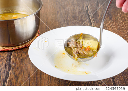 Ladle Leningrad Rassolnik soup into a plate. Ladle Leningrad Rassolnik soup into a plate. 124565039