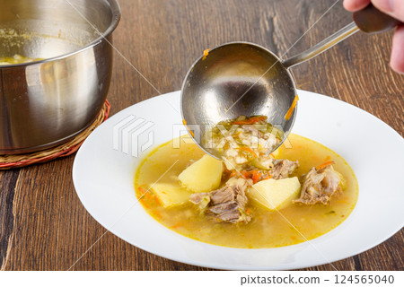 Pouring Leningrad Rassolnik soup from a ladle into a plate. Pouring Leningrad Rassolnik soup from a ladle into a plate. 124565040