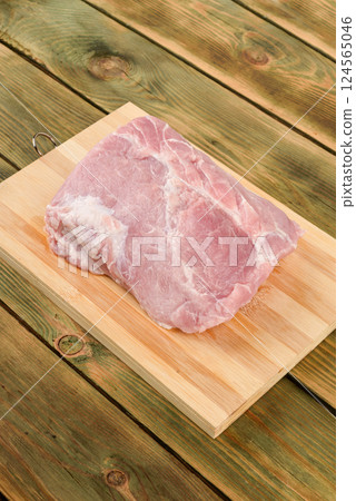 Top view of raw pork meat on wooden cutting board. 124565046