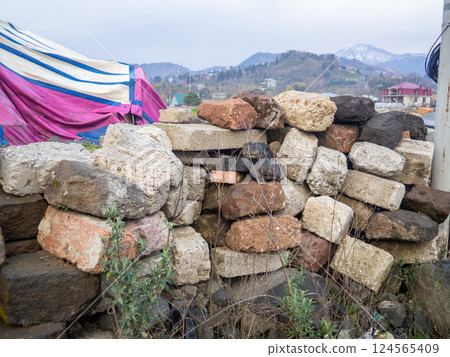 A pile of various stones stacked on top of each other. Masonry. Wall of stones.  fragile building 124565409