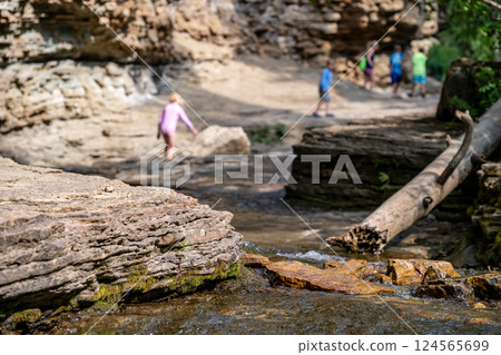 Selective focus on eroded Rock creek with defocused children on the trail to the Devils Bathtub waterfall in Spearfish Canyon, South Dakota Selective focus on eroded Rock creek with defocused children on the trail to the Devils Bathtub waterfall in Spearfish Canyon, South Dakota 124565699
