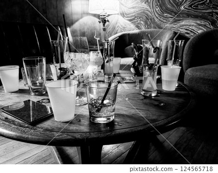 Scattered glasses and empty drinks on a bar table after a party Scattered glasses and empty drinks on a bar table after a party 124565718