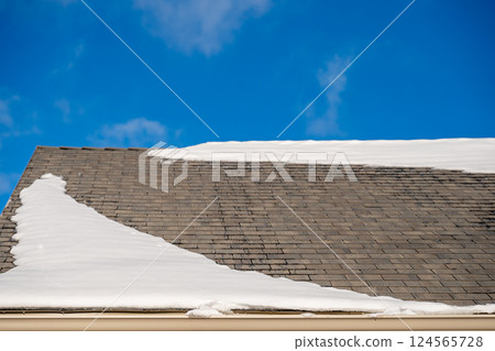 Snow and ice along a residential roof gutter forming a dam in the winter. Snow and ice along a residential roof gutter forming a dam in the winter. 124565728