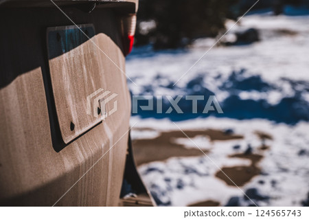Mud and dust covered vehicle license plate from a gravel road.  124565743