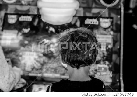 Selective focus on children playing arcade games for fun with blurred screen in background Selective focus on children playing arcade games for fun with blurred screen in background 124565746