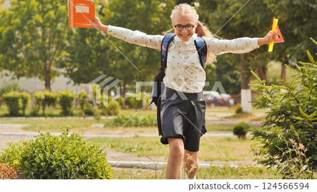 Happy eleven-year schoolgirl runs with a backpack after school. 124566594