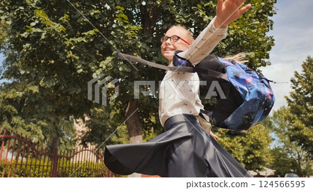 Cheerful schoolgirl sprinting, celebrating freedom after classroom hours, radiating joy 124566595