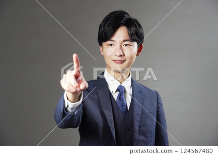 Businessman making a gesture of pressing a switch with his index finger, black background Businessman making a gesture of pressing a switch with his index finger, black background 124567480